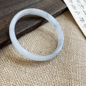 Macro di un bracciale in calcedonio grigio traslucido su uno sfondo rustico elegante