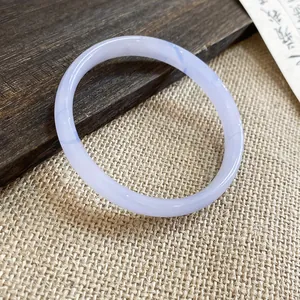 Primo piano di un elegante bracciale in calcedonio lavanda su sfondo di legno e tessuto.