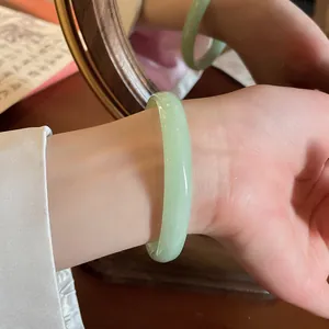 Primo piano di un elegante bracciale in calcedonia verde chiaro al polso con riflesso