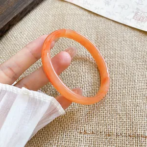 Dettaglio ravvicinato di un bracciale in calcedonio arancione traslucido su iuta