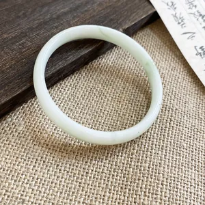 Dettaglio di un elegante bracciale tondo in calcedonia verde chiaro su sfondo zen