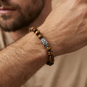 Men's Tiger Eye beaded bracelet with a silver Buddha head charm on a model's wrist