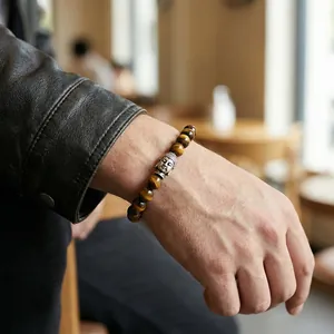 Men's tiger eye beaded bracelet with silver Buddha head pendant on a male wrist