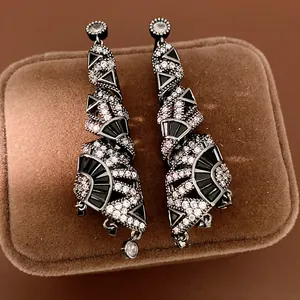 Primo piano di eleganti orecchini pendenti in zirconia nera dal design geometrico.