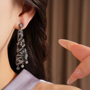 Dettaglio di eleganti orecchini pendenti a spirale in zircone nero indossati da una modella