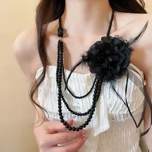Primo piano di un elegante collana multifilo nera con fiori in pizzo e piume delicate