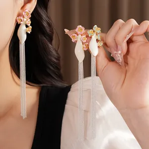 Détail rapproché de boucles d'oreilles vintage en émail avec de longs glands à chaîne