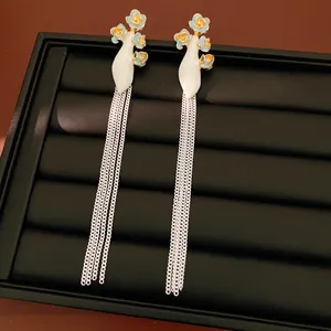 Détail de boucles d'oreilles vintage à fleurs et longues pampilles argentées sur socle