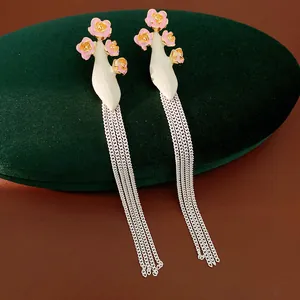 Détail macro de boucles d'oreilles vintage à fleurs roses et longs glands argentés