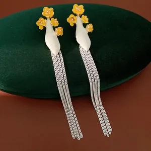 Gros plan détaillé de boucles d'oreilles vintage en émail avec fleurs et longues franges.