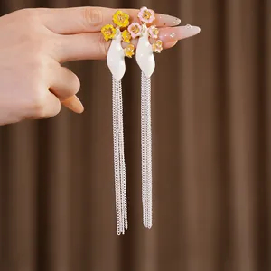 Gros plan de boucles d'oreilles vintage fleurs émaillées et longs glands