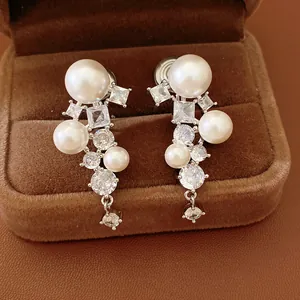 Detailed view of elegant zircon and pearl clip-on earrings in a brown velvet box.