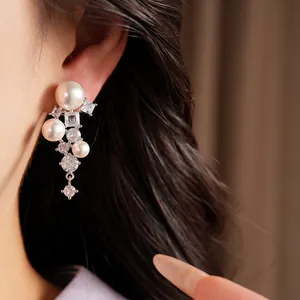 Detailed macro view of elegant geometric zircon and pearl clip-on earrings worn on a model's ear