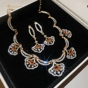 Elegant gold-toned luxury fan-shaped crystal necklace and earring set with orange center stones