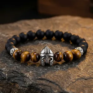 Macro detail of men's Viking style bracelet with Spartan helmet charm and tiger eye stones