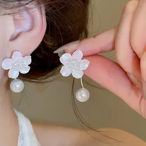Detailed view of elegant pink enamel flower earrings with pearl drops and zircons