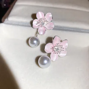 Close-up detail of elegant pink enamel flower earrings with zirconia and hanging white pearls