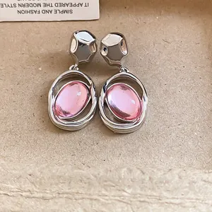 Macro view of silver-toned stud earrings featuring unique oval pink acrylic pendants