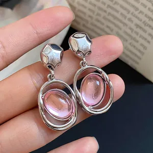 Macro view of unique pink oval acrylic dangle earrings with silver needle studs
