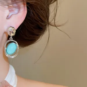 Elegant close-up of vintage style oval turquoise acrylic drop earrings worn on a model's ear