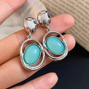 Close-up detail of silver-tone oval drop earrings featuring translucent light blue acrylic stones