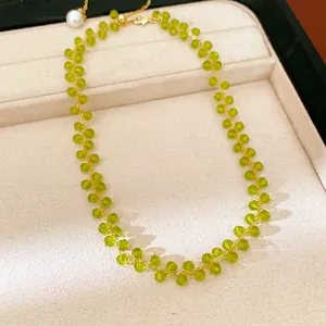 Close-up of 14k gold plated necklace with green glass beads on beige jewelry tray