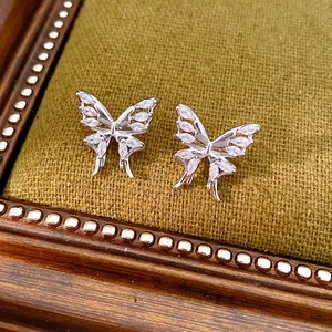 Eleganti orecchini a farfalla in argento con zirconi su sfondo di velluto