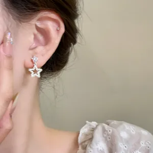 Primo piano di un orecchino a stella in argento con zirconi sull'orecchio del modello