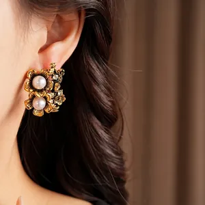 Elegant vintage gold floral stud earrings with white pearls and crystals on model
