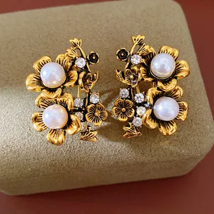 Macro view of vintage gold-tone floral stud earrings with white pearls and crystals.