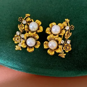 Macro view of vintage gold floral earrings featuring white pearls and sparkling rhinestones