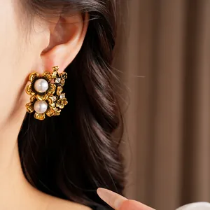 Detailed view of vintage gold flower earrings with pearls and rhinestones on model