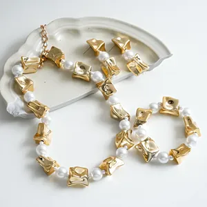 Close-up of gold crinkled square and pearl jewelry set necklace and bracelet