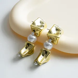 Close-up detail of vintage style gold wrinkled square earrings with elegant pearl accents