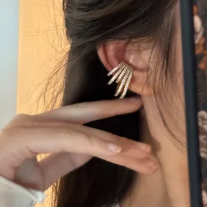 Detailed close-up showing a gold multi-layer zircon ear cuff worn on the upper ear bone