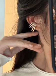 Detailed close-up showing a sparkling multi-layered gold zircon ear cuff worn on an ear bone