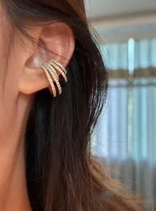 Multi-layer gold ear cuff encrusted with sparkling zircons shown on model's ear.