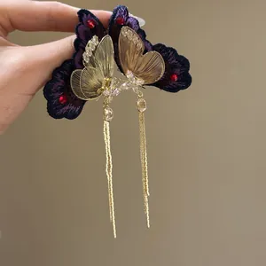 Detailed view of elegant purple butterfly earrings with long gold tassels and zircons