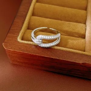 Detail view of silver-tone geometric hollow ring with sparkling zircon in wooden box