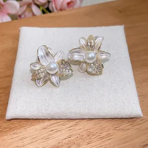 Eleganti orecchini a lobo a fiore con zirconi e perla centrale su display in tessuto