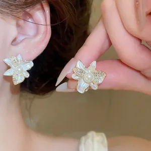 Dettaglio dell'orecchino a fiore in smalto bianco con perla e zircone