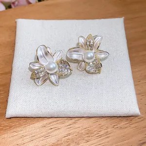Vista dettagliata di eleganti orecchini a fiore con petali in smalto bianco e perle