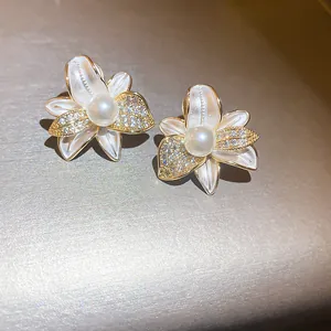 Primo piano di eleganti orecchini a lobo a fiore con zirconi e perla centrale.