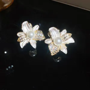 Dettaglio di eleganti orecchini a fiore con perle lucide e zirconi cubici scintillanti
