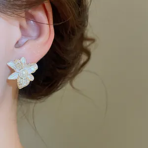 Primo piano di un elegante orecchino a fiore con dettagli in perla e zircone sull'orecchio
