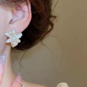 Dettaglio ravvicinato di un orecchino a fiore bianco con zirconi scintillanti e perla