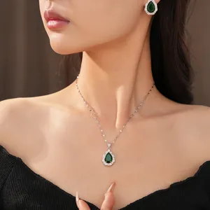 Close-up of elegant emerald green teardrop pendant necklace and stud earrings set