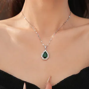 Close-up of elegant emerald pear-shaped pendant necklace with zirconia halo on model