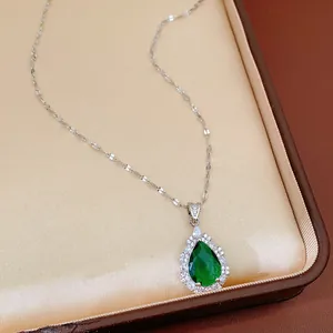 Close-up of elegant teardrop necklace with green emerald-cut zircon in display box