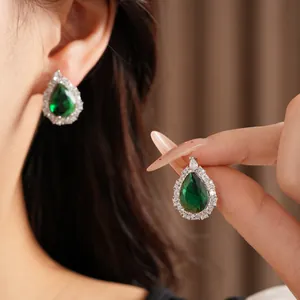 Detailed view of elegant emerald green teardrop stud earrings with cubic zirconia halo.